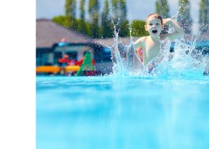 Happy boy jumping into a pool