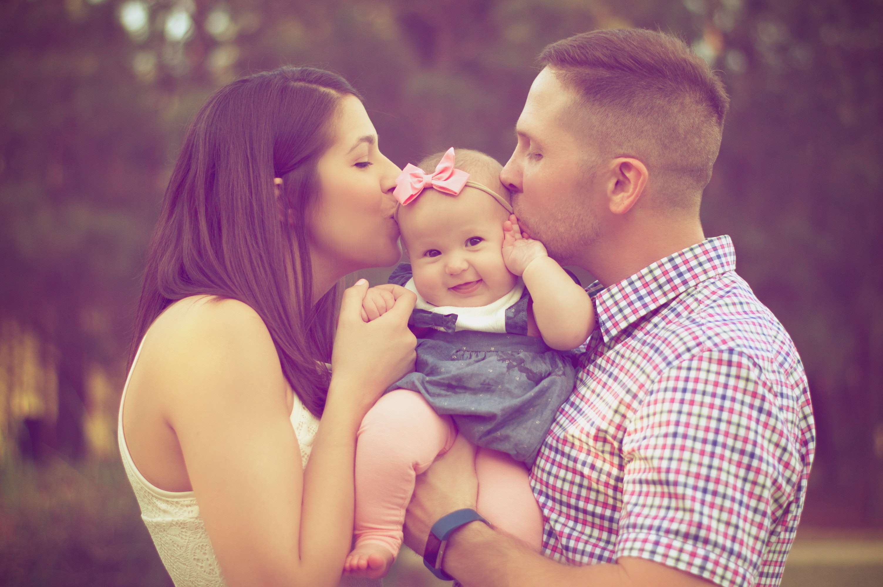 family of three with baby smiling at the camera