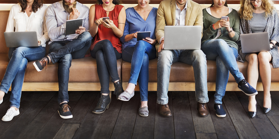 people on various mobile devices sitting on a bench