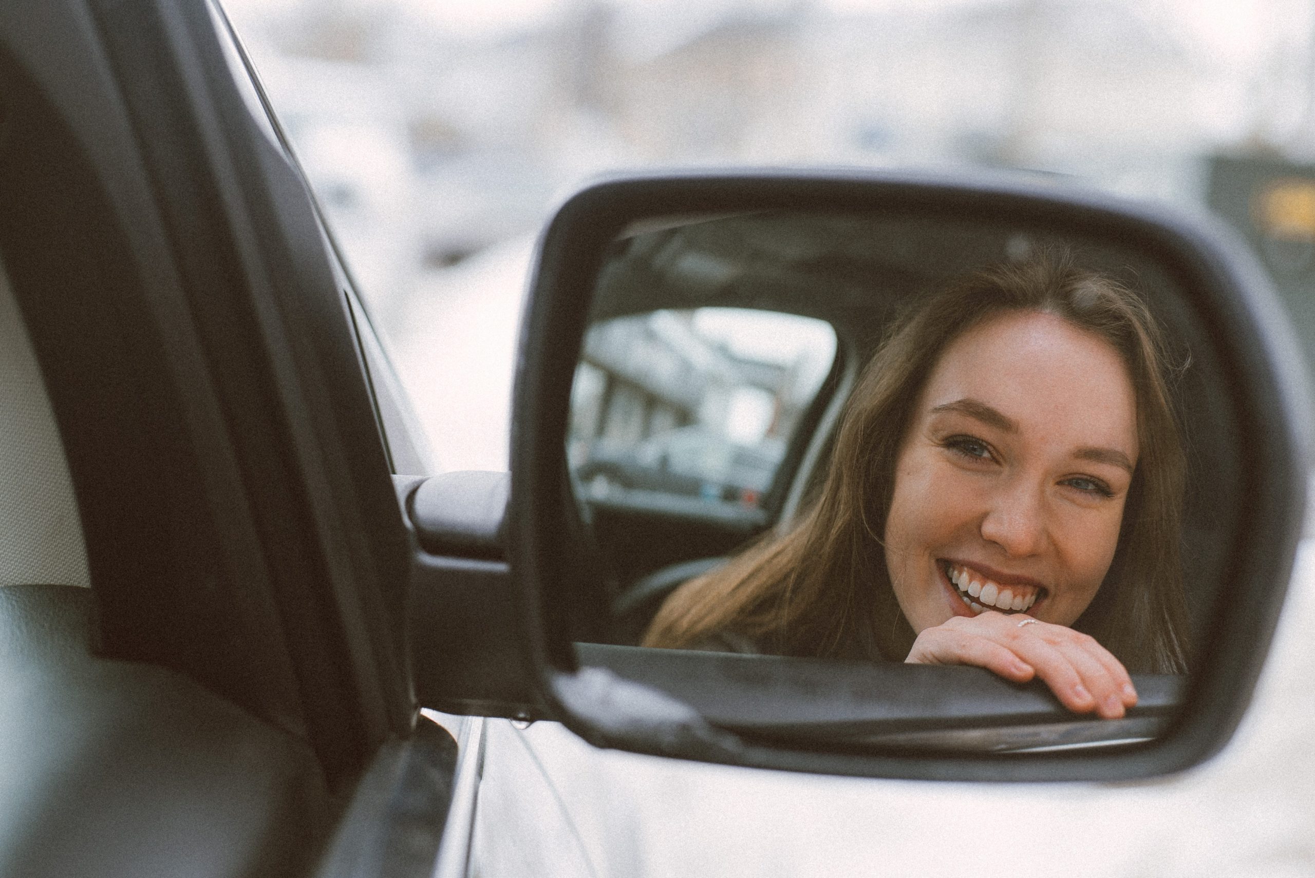 buy a car image - women smiling in car mirror