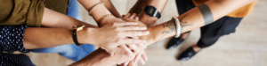 Several people with hands in the middle in a symbolic gesture of teamwork