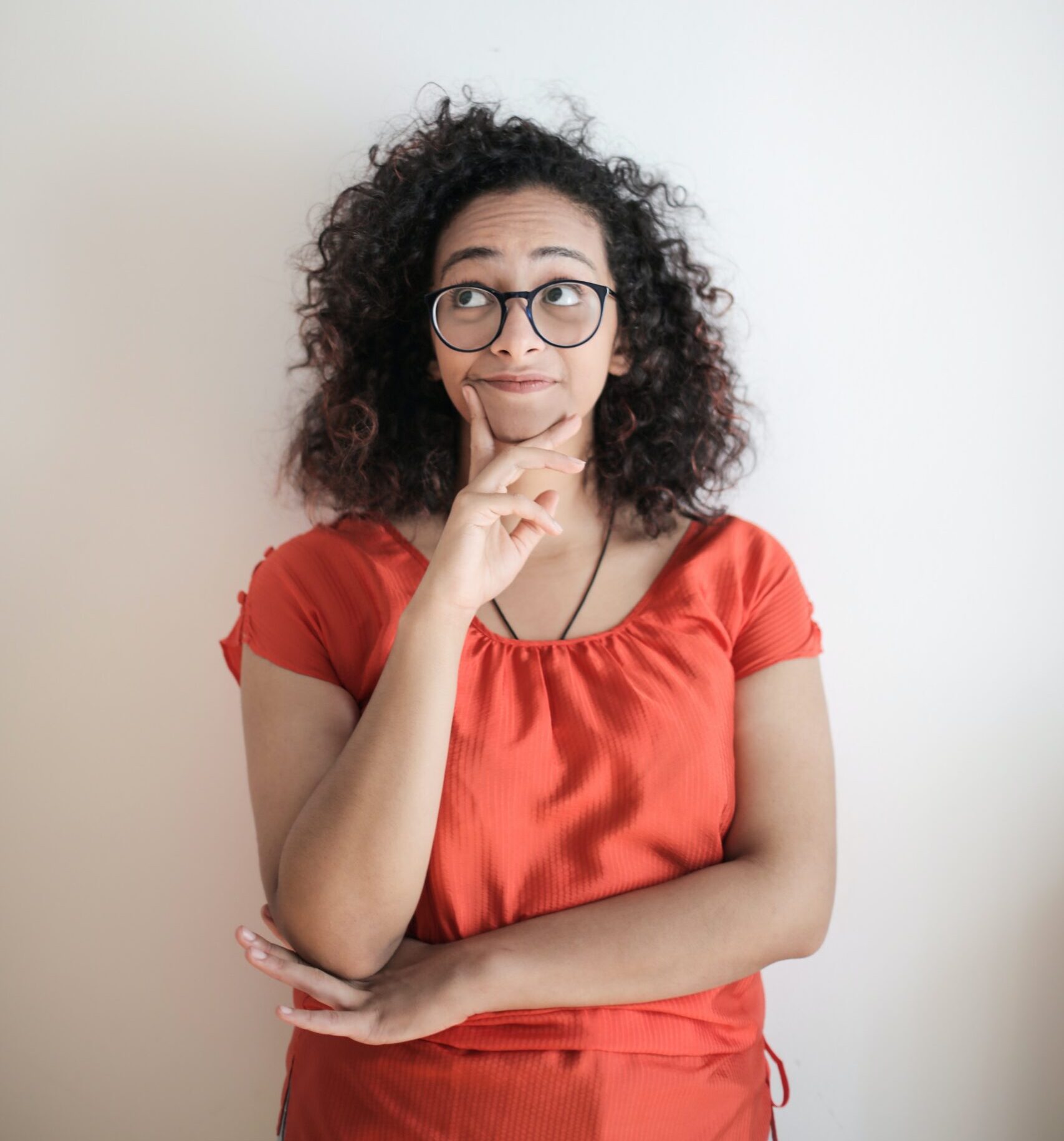 woman with curly hair and glasses looking contemplative