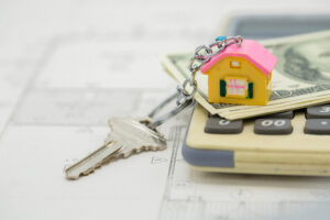 House key chain and key sitting on top of money and a calculator